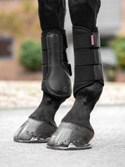 Horse wearing black LeMieux Mesh Brushing Boots standing on pavement