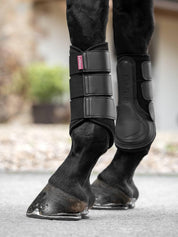 Horse wearing black LeMieux Mesh Brushing Boots walking on pavement