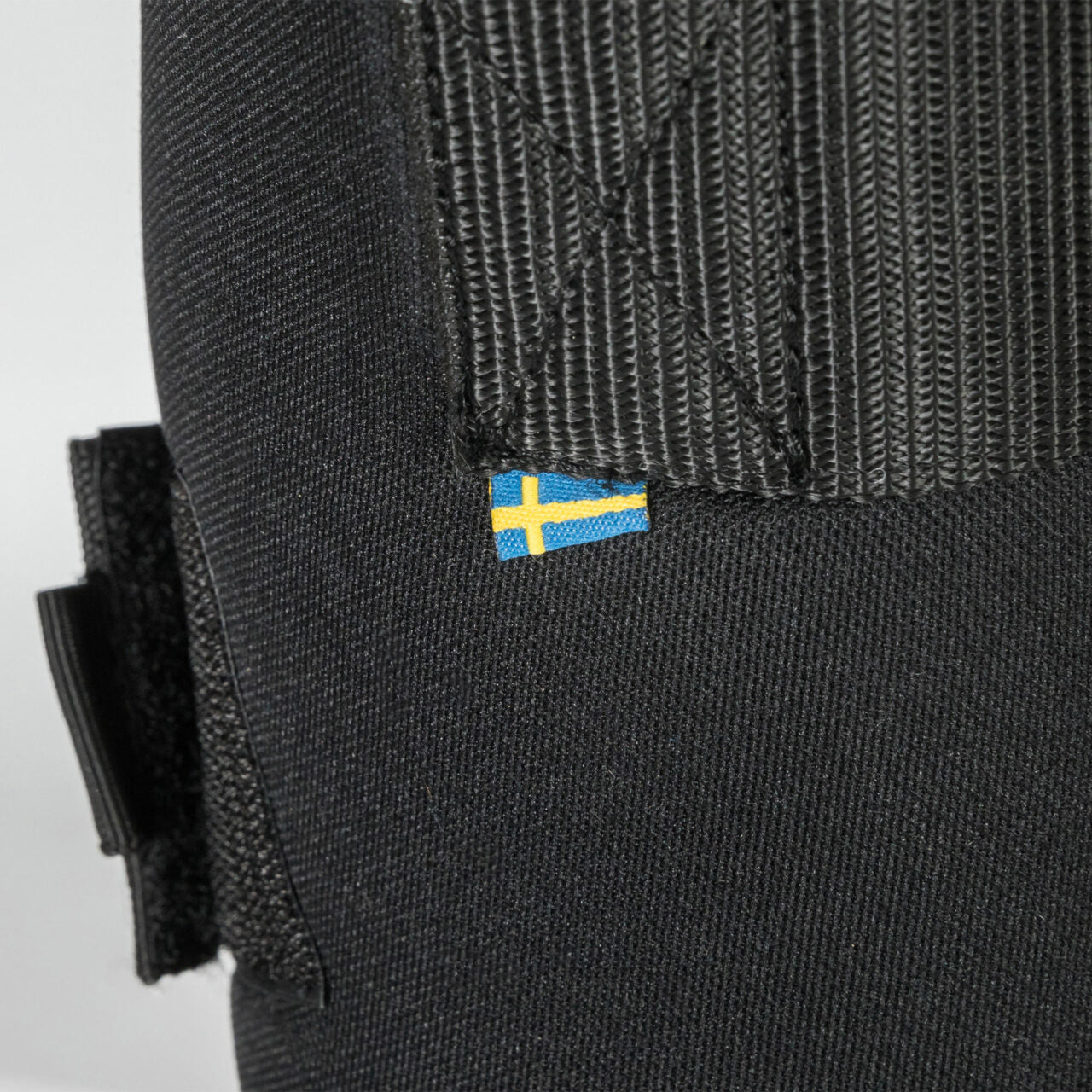 Close-up view of the Sweden flag tag on a black Back On Track Royal Quick Wrap