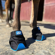 Close-up angled front view of a brown horse wearing the EasyCare Easyboot Zip Horse Boot while standing on rubber mats outside