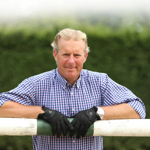 Front view of a man standing outside resting his arms over a jump while wearing the black SSG Digital Gloves
