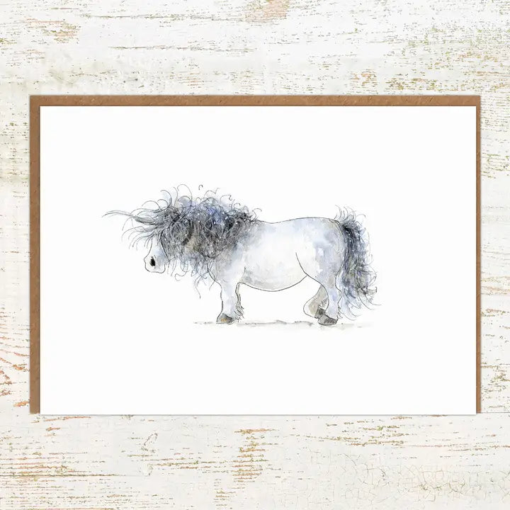 View of the Unicorn Pony Nut Greeting Card on a white washed wood background