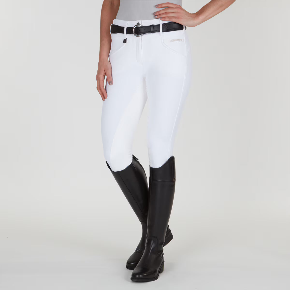 Front view of a model wearing the white Romfh Champion Full Seat Breech and black tall boots on a plain background