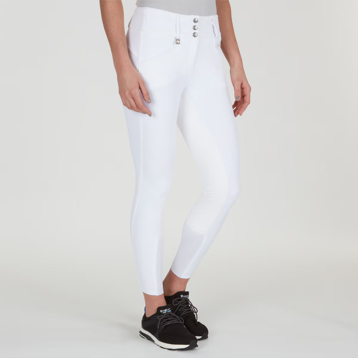 Angled front view of a model wearing the white Romfh Champion Full Seat Breech and black tennis shoes on a plain background