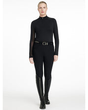 Full body view of a model wearing the black LeMieux Halle Lightweight Base Layer, black breeches, and black tall boots on a white background