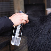Hand spraying Hairy Pony Detangle & Shine Spray on a horse's tail