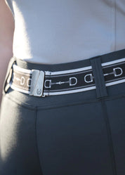 Close-up view of the black Kerrits Kids Snaffle Stretch Belt over gray breeches