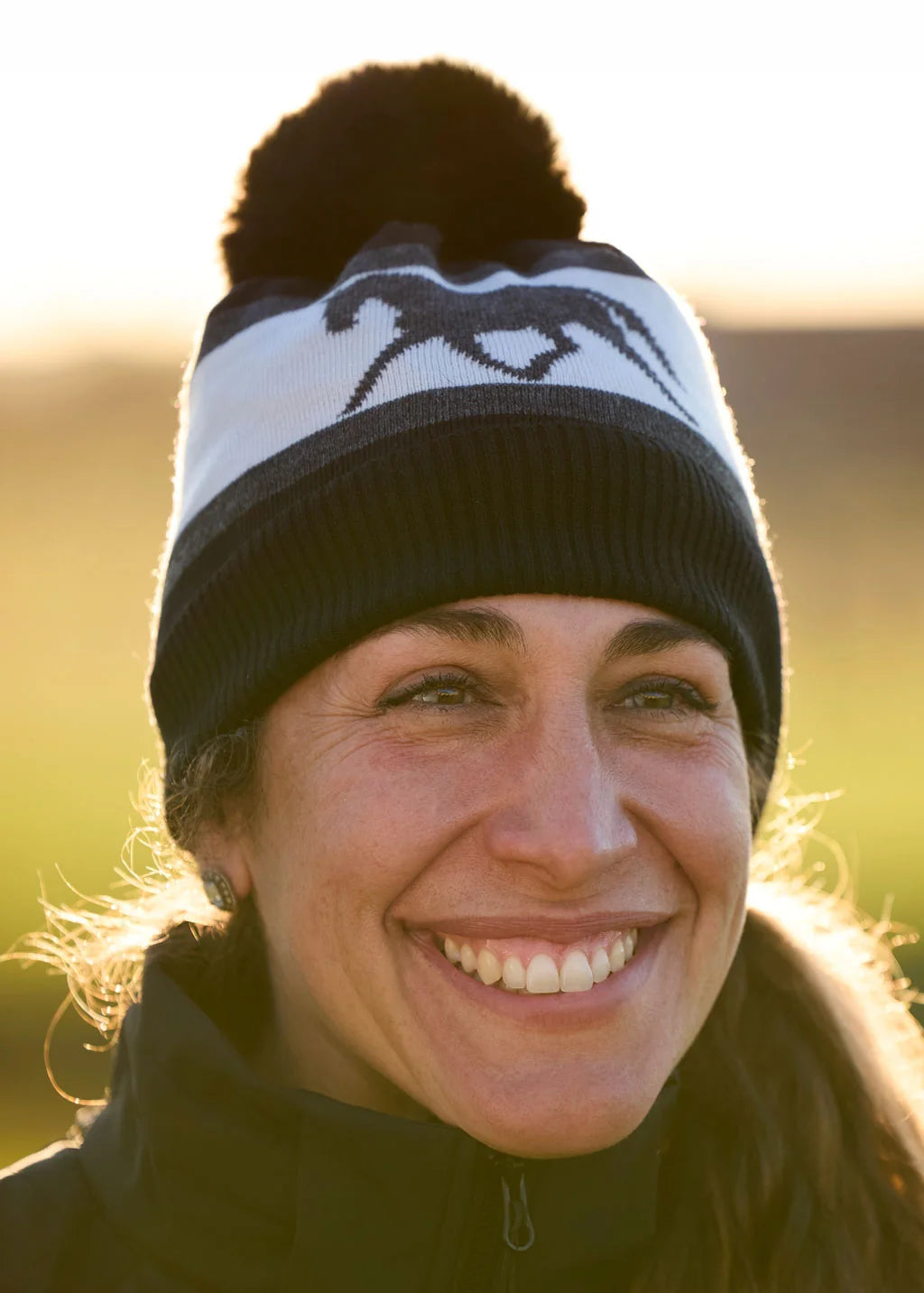 Front view of a female model wearing the black Kerrits Pony Pom Winter Hat outside