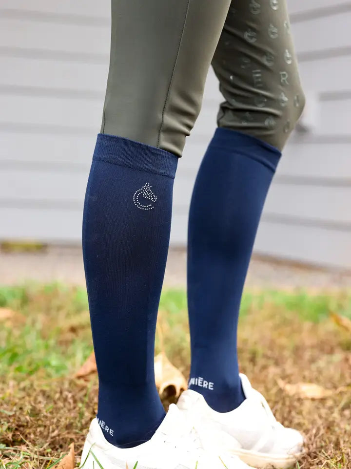 Side view of a model wearing the navy Criniere Equestrian Socks with white sneakers while standing in the grass