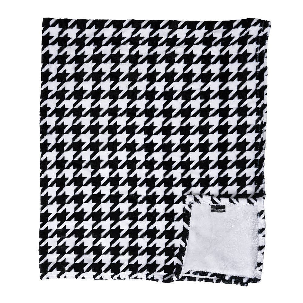 View of the folded up Blue Stallion Farm Black & White Houndstooth Flannel Fleece Blanket in Leather Holder on a white background