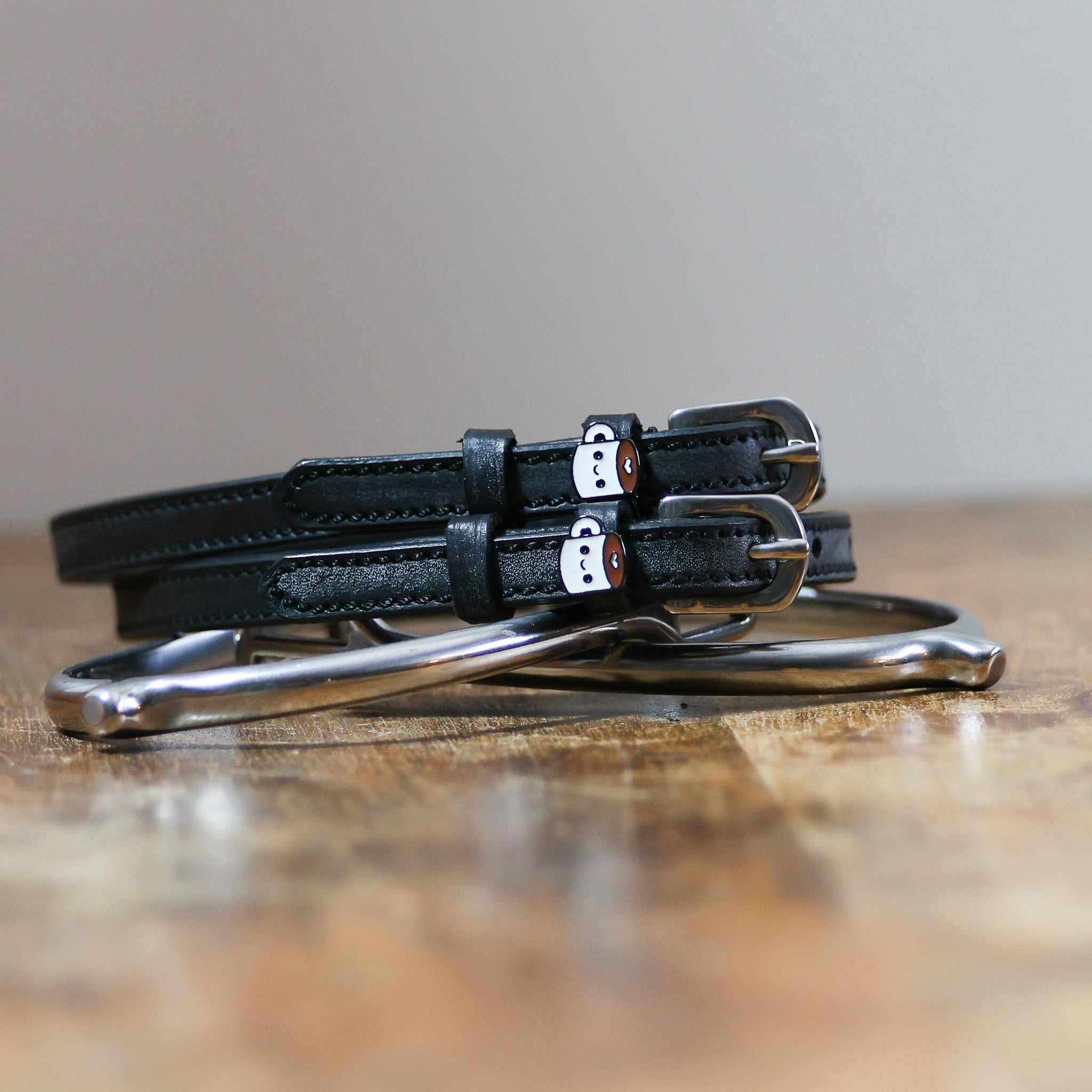 Front view of the buckled Coffee Mane Jane Spur Straps on wood
