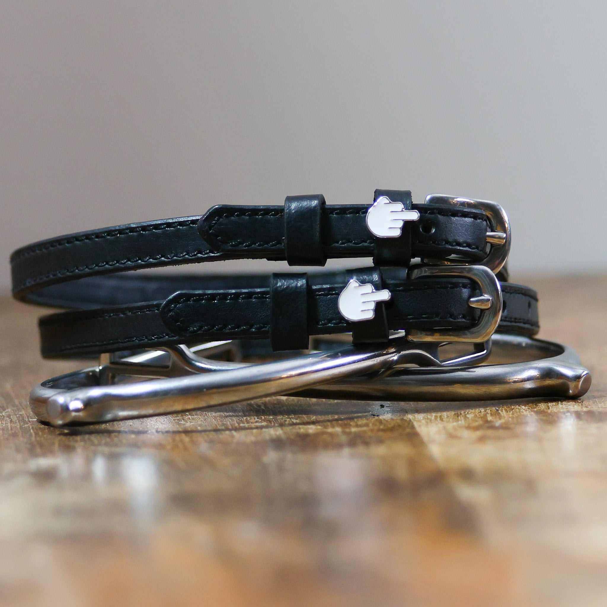 Front view of the buckled Middle Finger Mane Jane Spur Straps on wood
