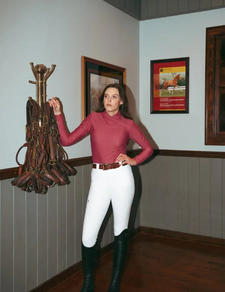 Front view of a female model wearing the cherry blossom Criniere Kai Shirt while standing in a tack room