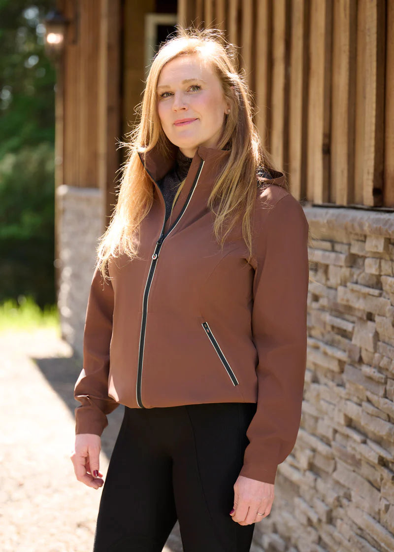 Woman standing outdoors wearing a brown waterproof jacket