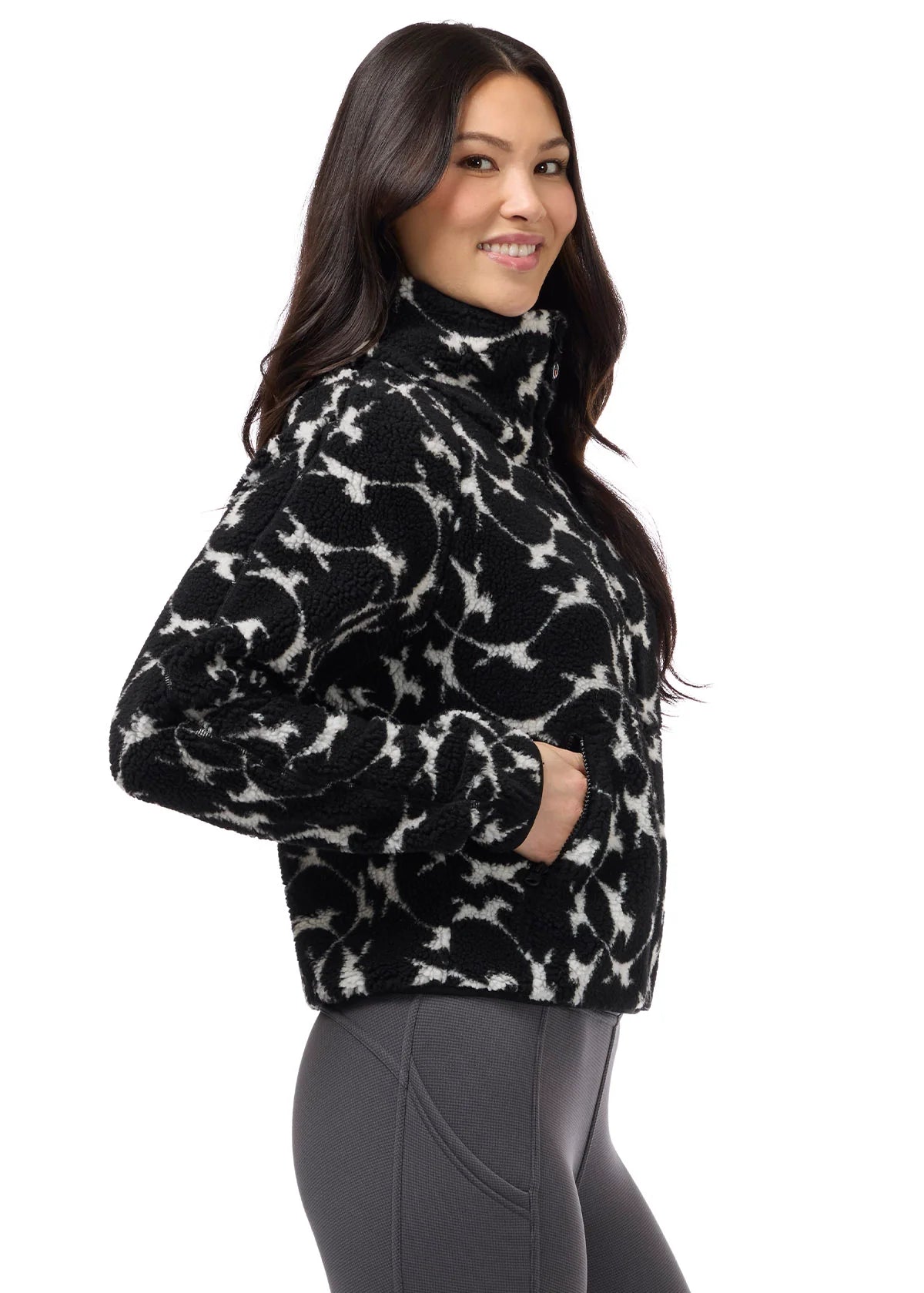 Side view of a female model wearing the Kerrits Berber Flying Horse Jacket on a plain background