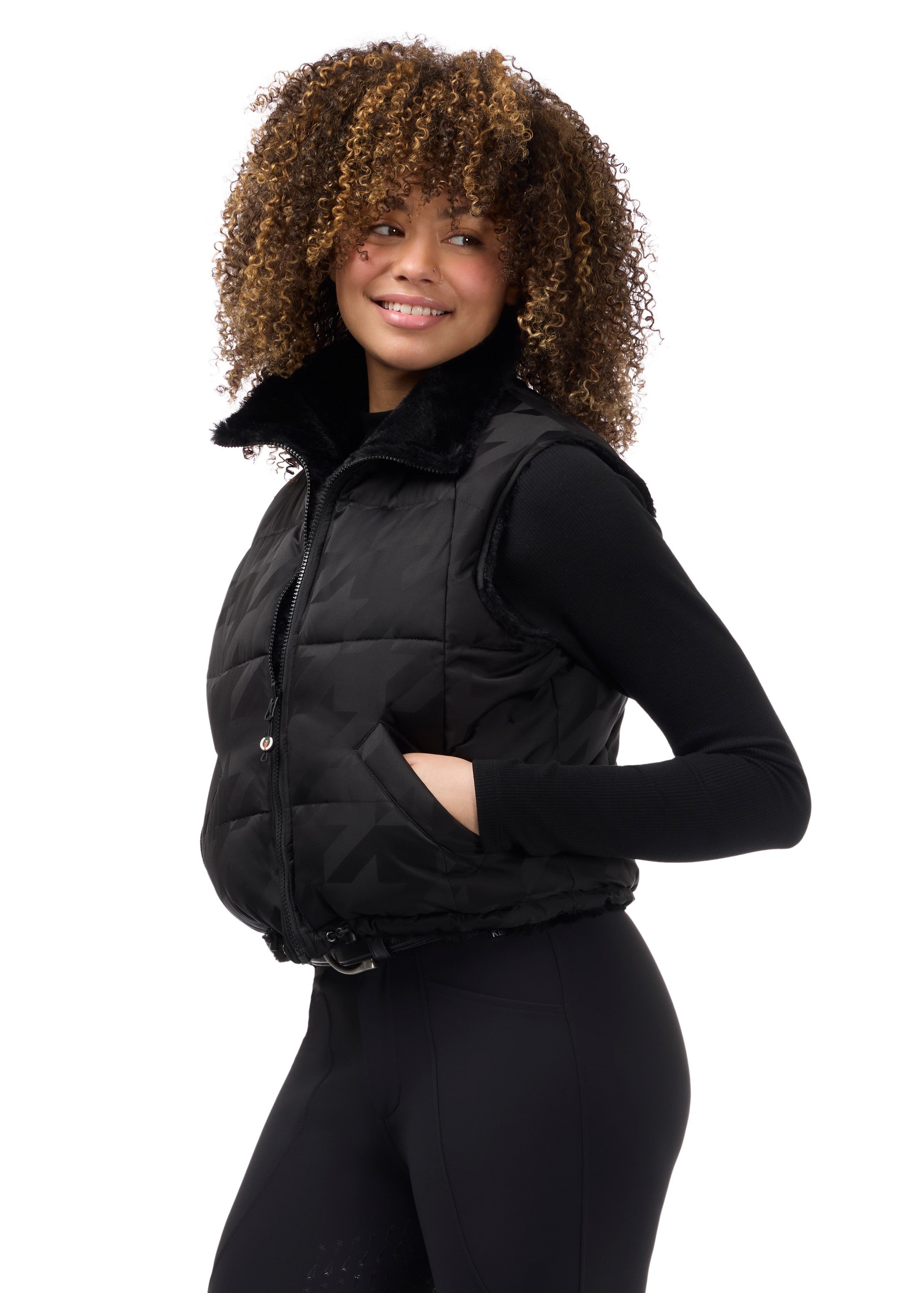 Angled front view of a model wearing Black Kerrits Skyline Houndstooth Reversible Vest on a white background