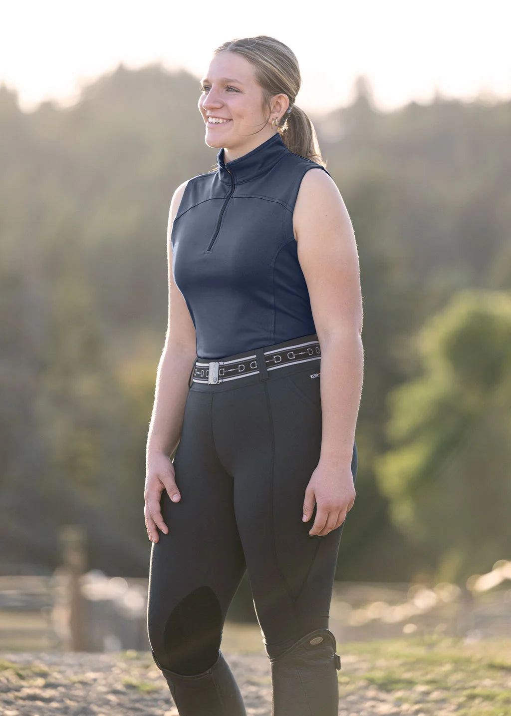 Angled front view of a model wearing the Neptune Kerrits Quarter Zip Performance Sleeveless Top while standing outside