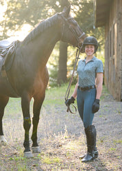 Woman leading a horse while wearing a blue riding shirt