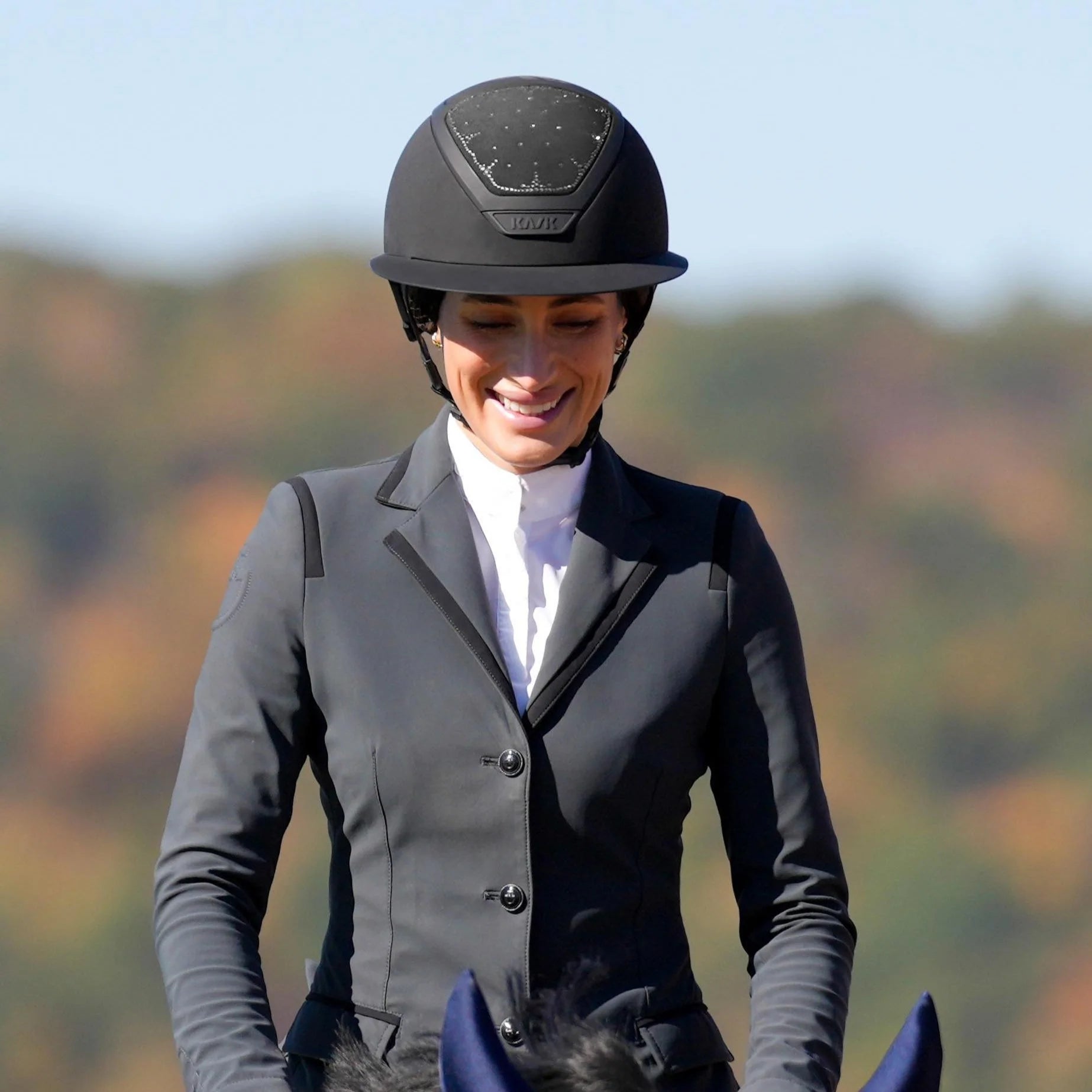 Front view of a female rider wearing the Kask Star Lady Jessica Springsteen Edition while riding a horse outside
