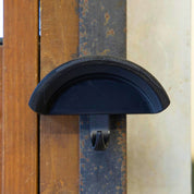 Close-up view of the black Correct Connect Magnetic Bridle Holder with Hook on a metal surface in a barn