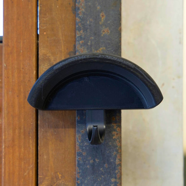 Close-up view of the black Correct Connect Magnetic Bridle Holder with Hook on a metal surface in a barn