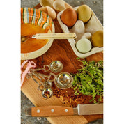 View of the Blue Stallion Farm Equestrian Zinc Measuring Spoons with eggs and spices on a wooden cutting board