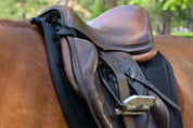 Angled front view of the black Correct Connect XC Mesh Saddle Pad under a brown saddle worn by a chestnut horse