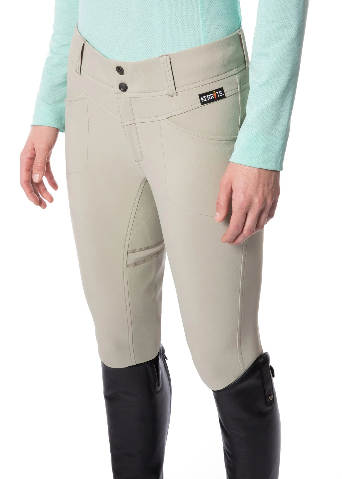 Angled front view of a model wearing the sand Kerrits Crossover II Full Seat Breech on a white background