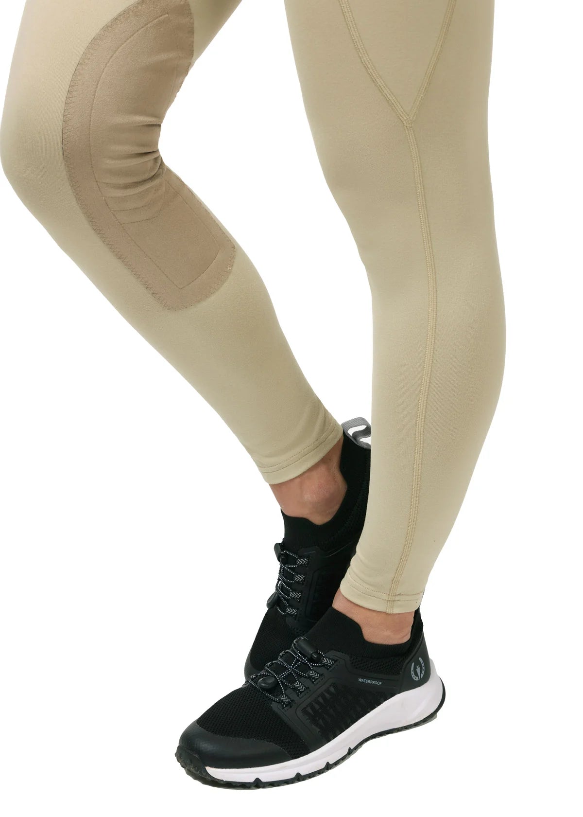 Close-up view of the lower leg on the tan Kerrits Performance Knee Patch Pocket Tight on a white background
