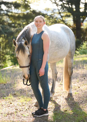 Woman standing beside a horse wearing blue printed riding tights