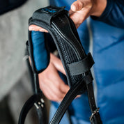 Close-up of Horseware Ionic Poll Cover attached to a black bridle, showing padded mesh lining and strap