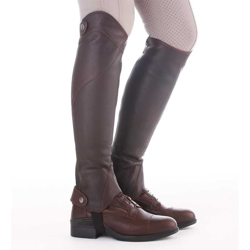 Side view of a model wearing the brown Kavalkade Remus Oiled Leather Half Chaps on a white background