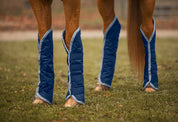View of a chestnut horse wearing the navy and gray Jacks Quilted Shipping Boots while standing outside on grass