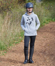 Young girl standing outside on a path wearing the black Kerrits Kids Fleece Lite II Knee Patch Tight and a gray equestrian hoodie