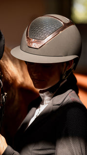 Angled front view of a model wearing the black and everyrose KASK Star Lady Chrome while standing next to a horse