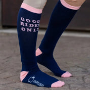 Side view of a model wearing the Good Rides Only Dapplebay Knit Boot Socks while standing in a barn aisle