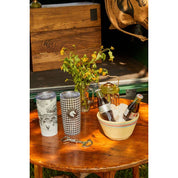View of the snaffle Blue Stallion Farm Zinc Bottle Opener on a wood table with drinkware