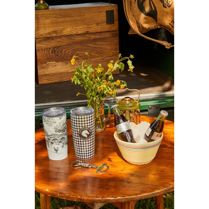 View of the snaffle Blue Stallion Farm Zinc Bottle Opener on a wood table with drinkware