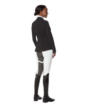 Full body angled back view of a female model wearing the white Kerrits Crossover II Full Seat Breech with black show coat on a white background