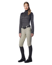 Full body front view of a female model wearing the sand Kerrits Crossover II Full Seat Breech with black patterned shirt on a white background