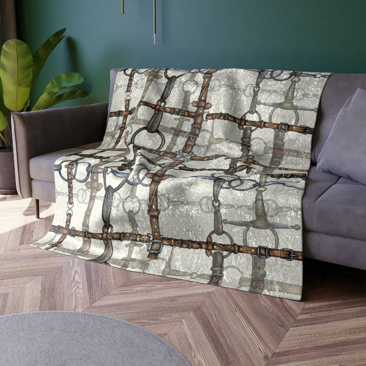 View of the All Designs Equine Ivory Bit Plaid Equestrian Crushed Velvet Throw on a gray couch