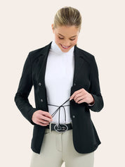 Front view of a female model wearing the black RJ Classic Addison Air Mesh Coat and adjusting the tie on her competition number tabard on a plain background