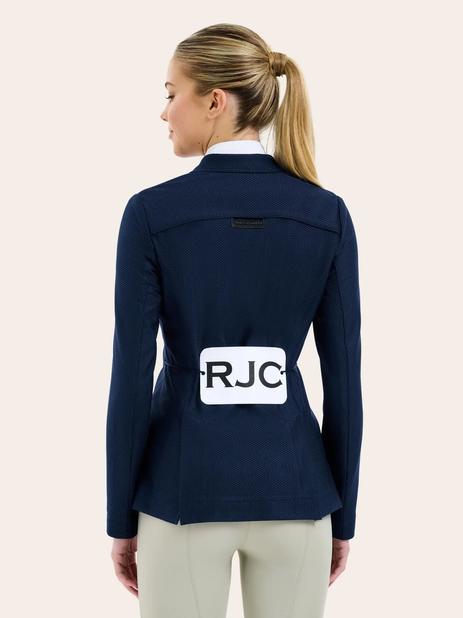 Back view of a female model wearing the navy RJ Classic Addison Air Mesh Coat with RJC on the competition number tabard on a plain background