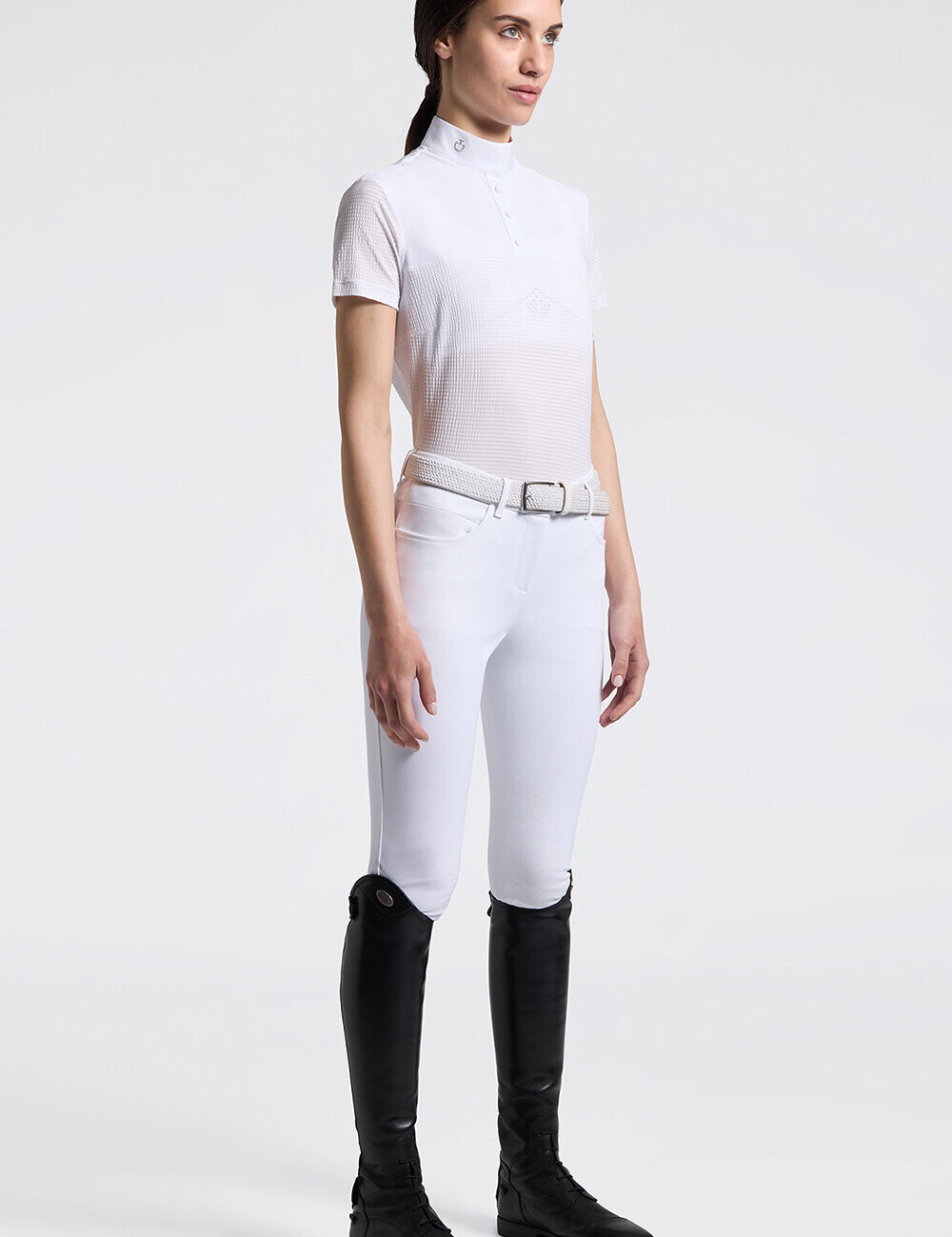Full body angled front view of a model wearing the white Cavalleria Toscana Short Sleeve Stripe Jersey Competition Shirt with white breeches on a plain background