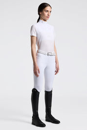 Full body angled front view of a model wearing the white Cavalleria Toscana Short Sleeve Stripe Jersey Competition Shirt with white breeches on a plain background