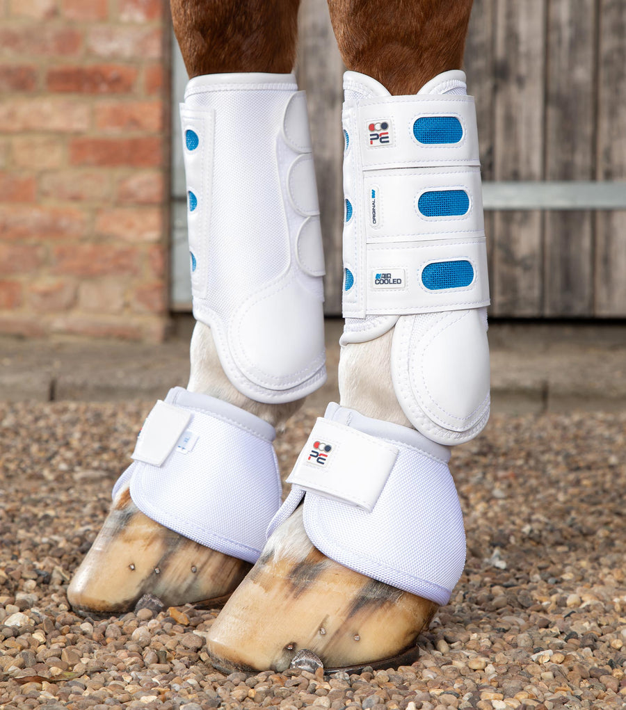 Side view of a horse wearing the white Premier Equine Air Cooled Original Eventing Front Boots while standing on pebbles