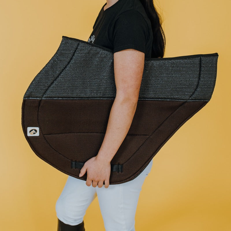Side view of a model holding the brown Ecogold Secure Cross Country Pad on a yellow background
