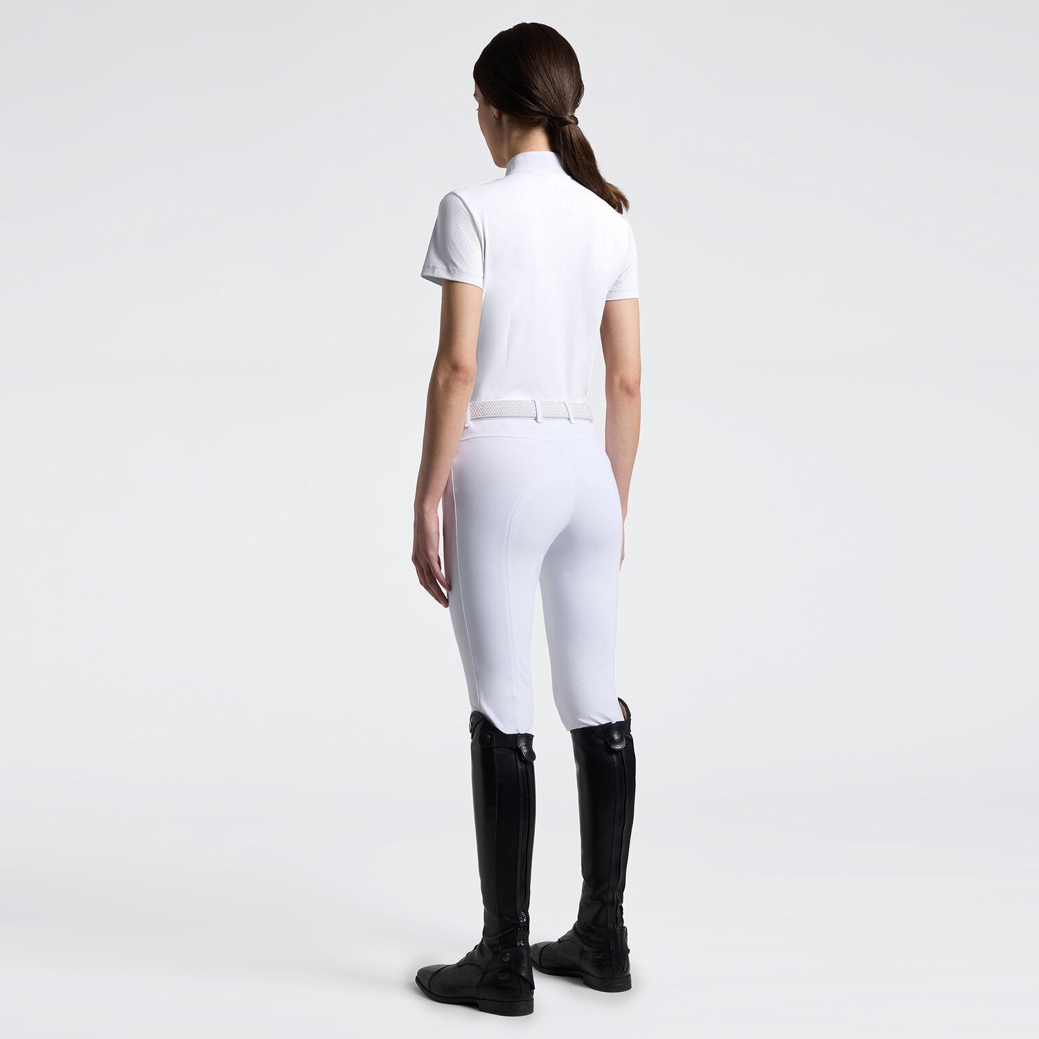 Full body back view of a model wearing the white Cavalleria Toscana Perforated Short Sleeve Competition Shirt and white breeches on a plain background