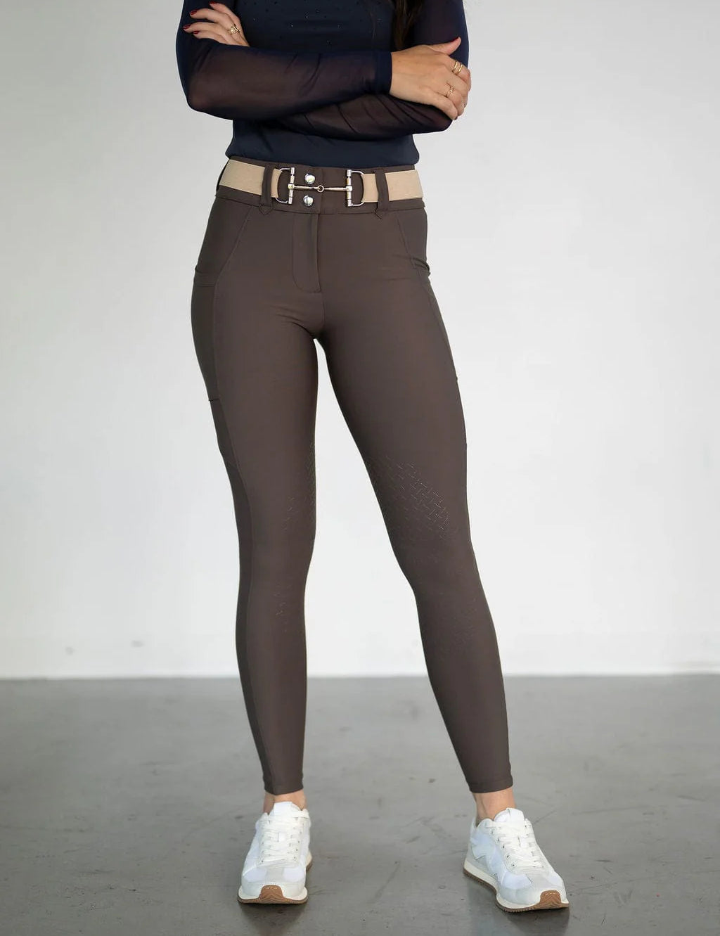 Front view of a female model wearing the brown Free Ride Lux Knee Patch Breeches in a studio setting