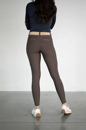 Back view of a female model wearing the brown Free Ride Lux Knee Patch Breeches in a studio setting